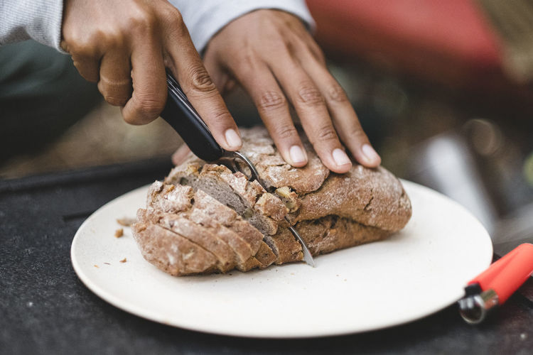 Closeup of women hands cutting bread outdoors