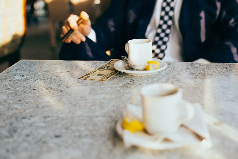Midsection of businessman with coffee on table at cafe