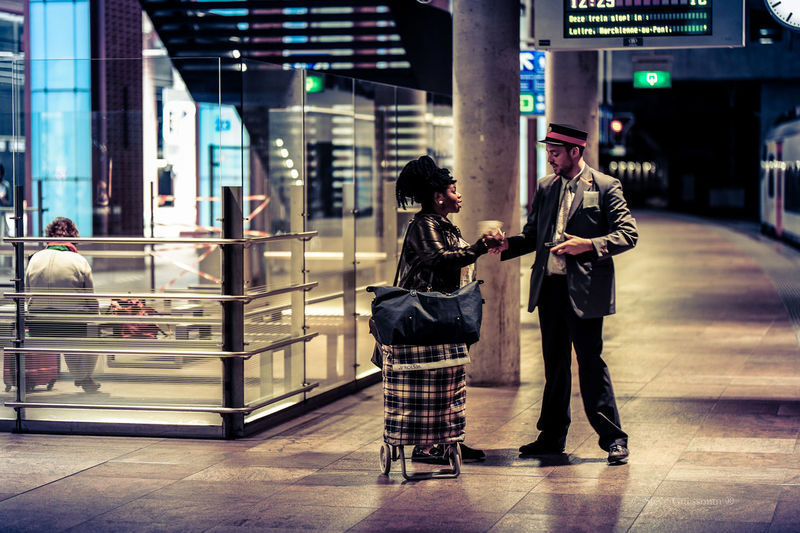 Woman giving paper currency to conductor at railroad station platform
