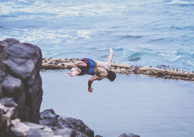 Boy jumping over sea