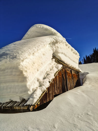 Snow covered built structure against clear blue sky