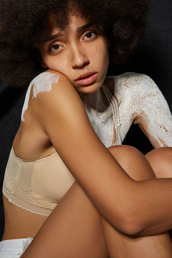 Portrait of woman with paint sitting against black background