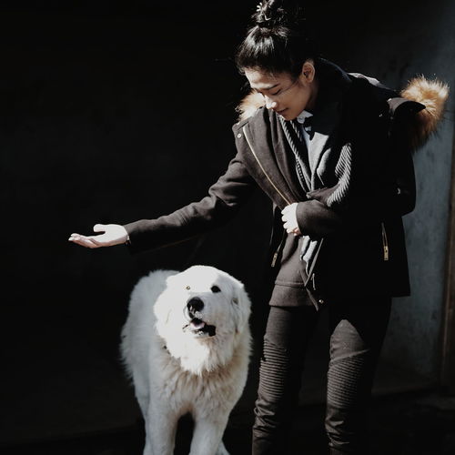 Full length of woman with dog against black background