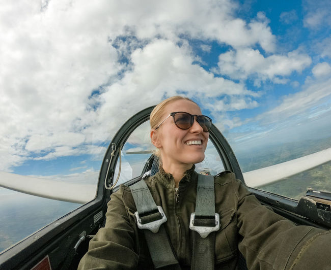 Woman flying airplane against cloudy sky