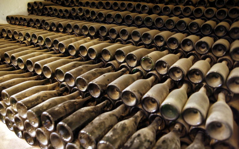 Stack of dust covered wine bottles in warehouse