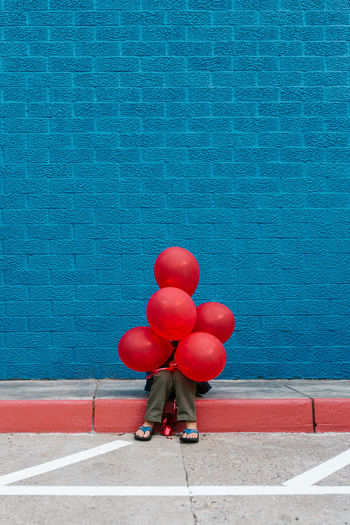 Man with red balloon balloons against blue water