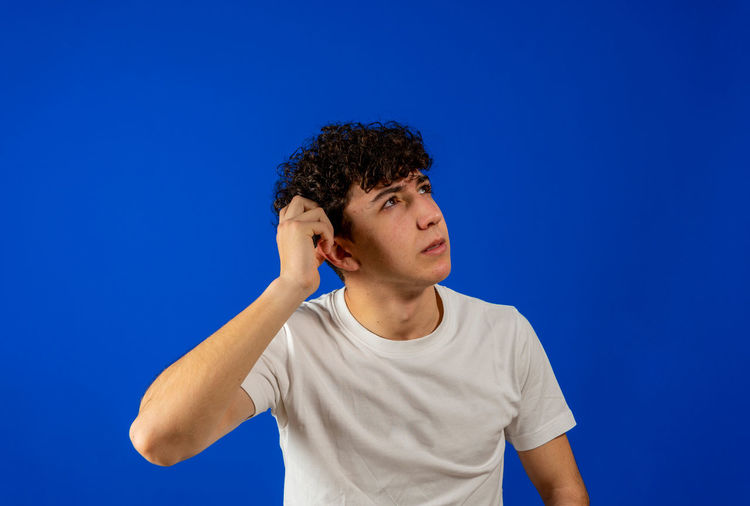 Portrait of teenage boy standing against blue background