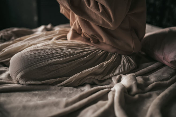 Midsection of woman relaxing on bed at home