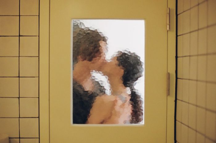 Couple kissing on the mouth seen through glass door