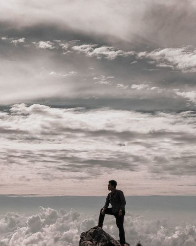 Full length of young man standing on rock against sky