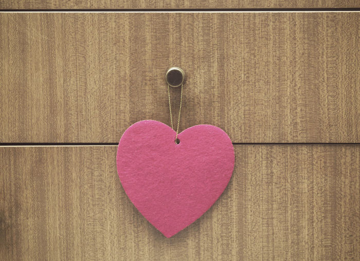 Close-up of heart shape on pink wood