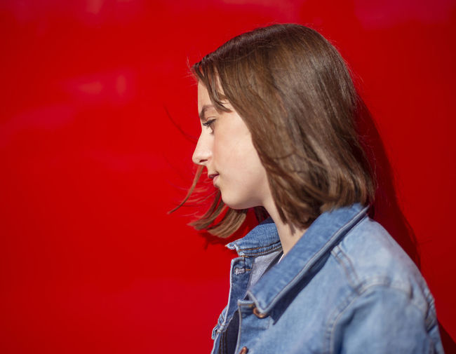 Portrait of woman against red background