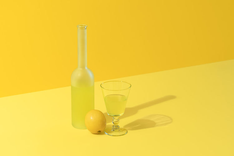 Close-up of glass bottle on table against yellow background