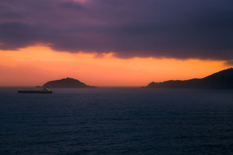 Portovenere gulf and la palmaria island during a cloudy orange sunset, la spezia, liguria, italy