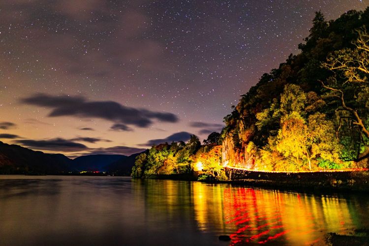 Ullswater under the night sky with car light trails reflection 