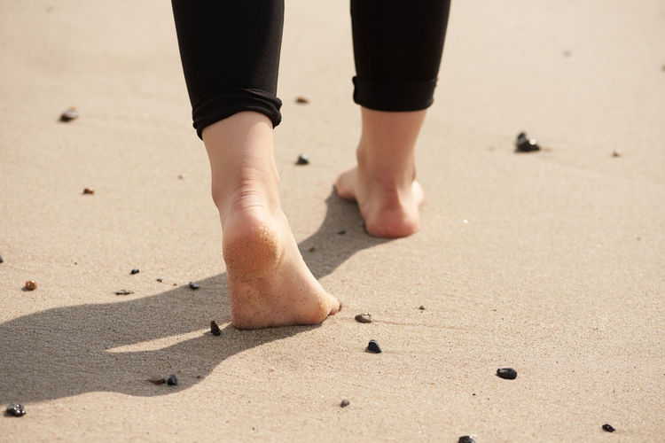 Low section of woman walking on sand