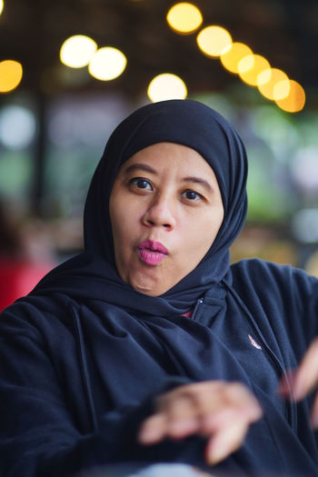 Portrait of indonesian muslim woman wearing black hijab with bokeh.