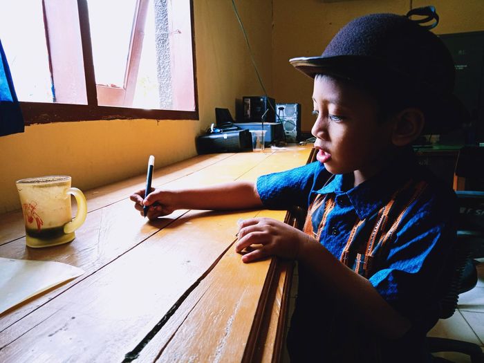 Boy writing on table at home