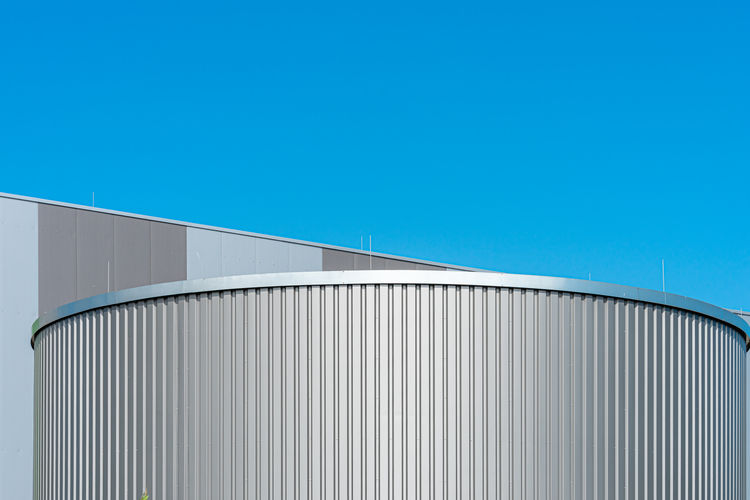 Low angle view of storage tank against clear blue sky