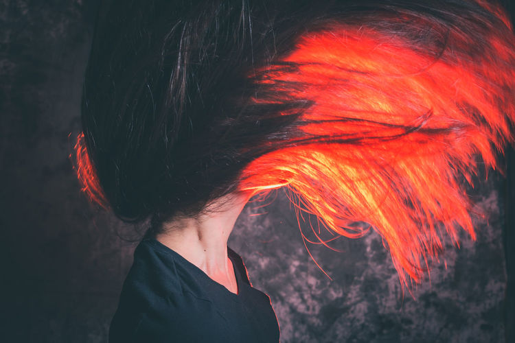 Woman tossing dyed hair against wall