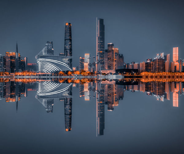 Reflection of illuminated buildings in river against sky