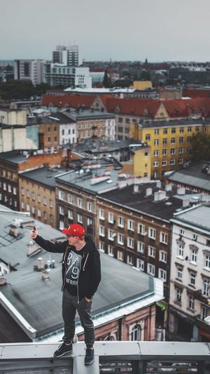 Full length of man standing on roof in city against sky