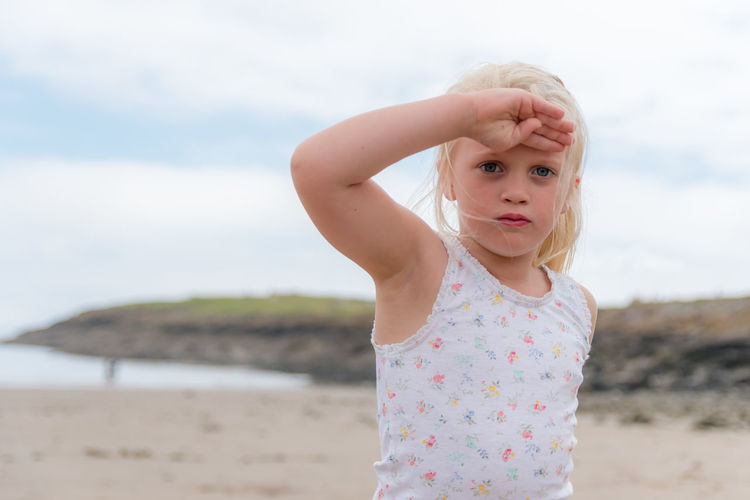 Portrait of cute girl saluting at beach