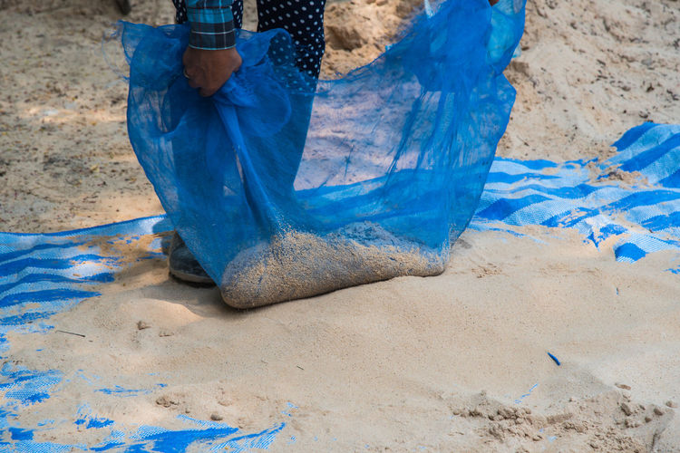 Low section of person cleaning sand at beach