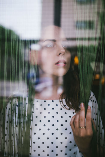 Portait of young woman standing between curtains