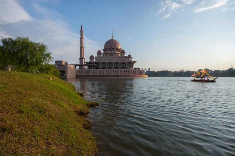 Putra mosque by lake against sky in city
