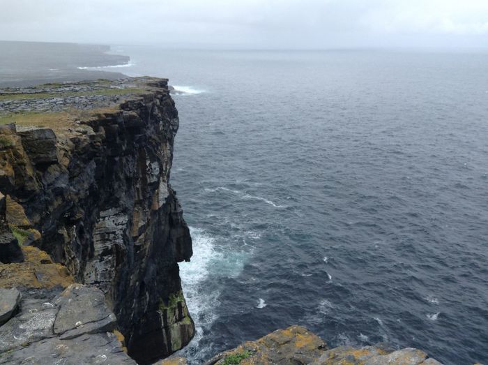 Scenic view of sea by cliff at aran islands against sky