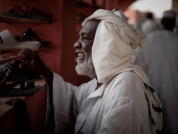 Rear view of sudanese old man smiling and looking at the window 