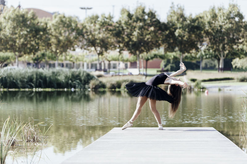 Woman ballet dancing on pier over lake