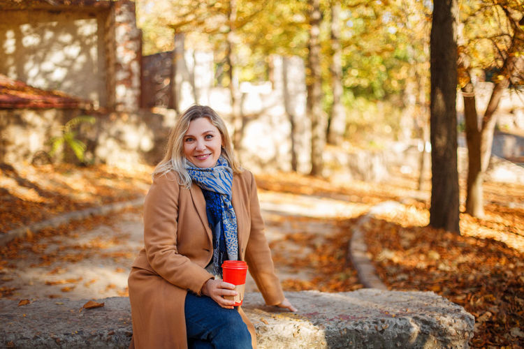 Portrait of smiling young woman in park during autumn