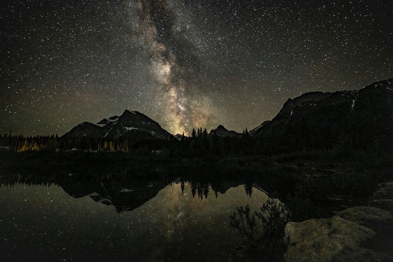 Scenic night shot of milky way over a mountain reflected in a still lake.