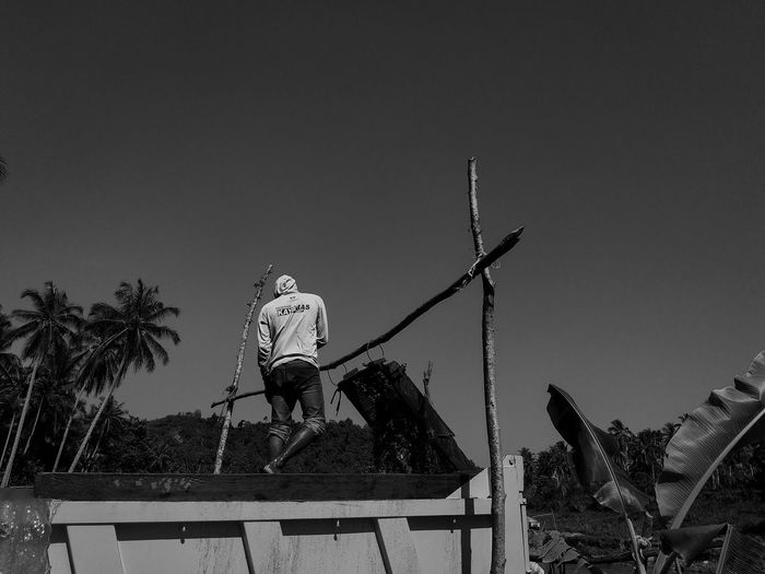 Low angle view of man working against clear sky