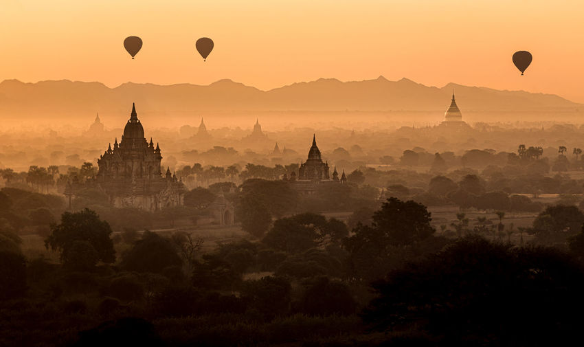 Hot air balloons flying against sky during sunset