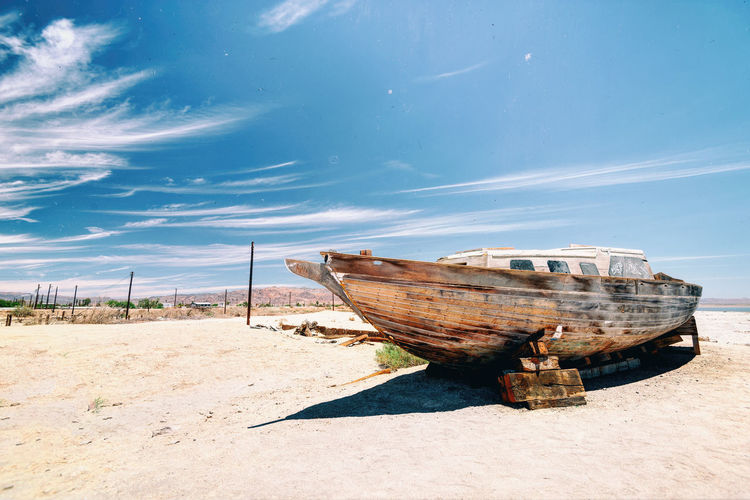Abandoned boats moored on beach against sky