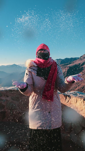 Woman standing on snow covered mountain against sky