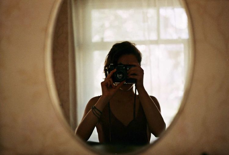 Close-up of young woman photographing through smart phone at home