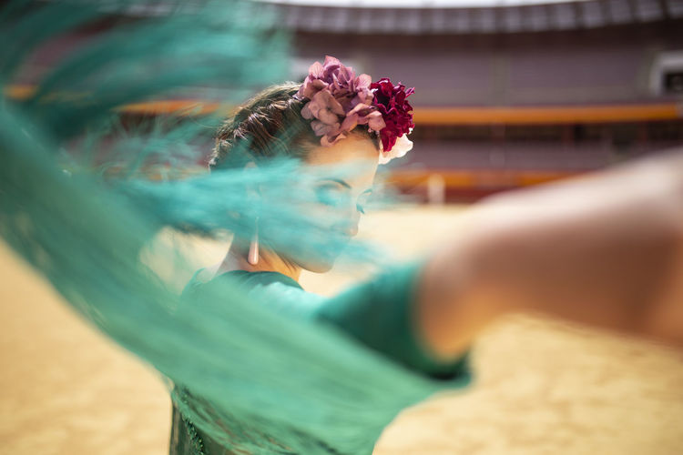 Close-up of flamenco dancer moving her dress's fringes while dancing in bullring