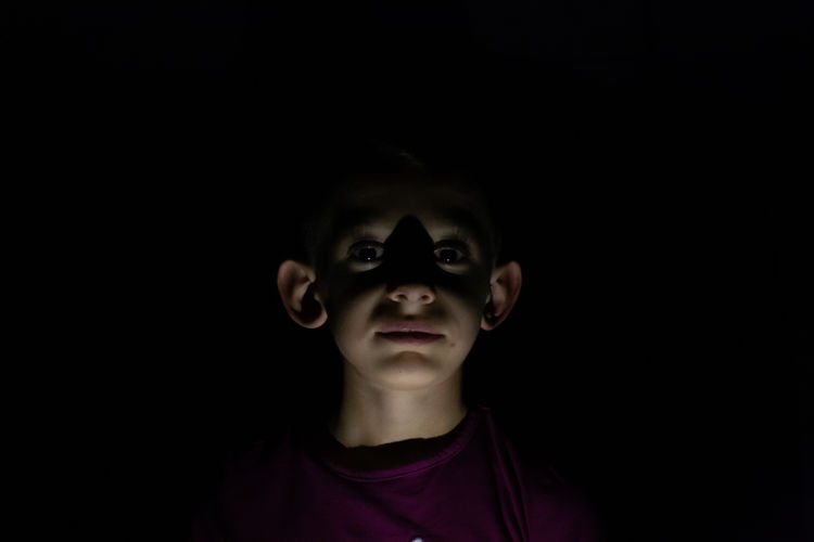 Portrait of boy against black background