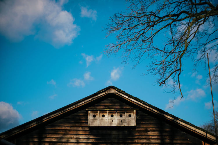 Roof of wooden house with birdhouses against blue sky