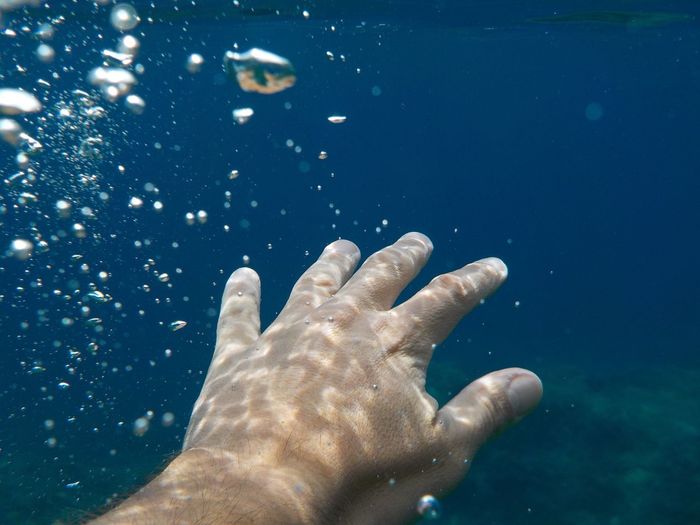 Close-up of hands in water against blue sky