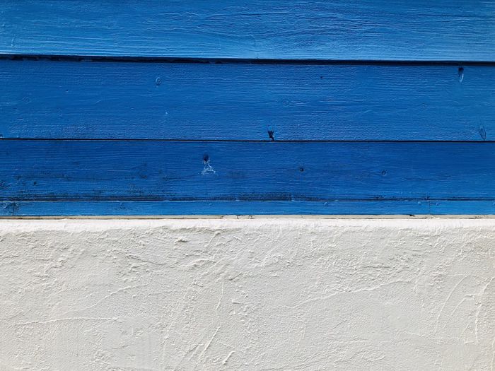 Full frame shot of blue color paint wooden wall and white cement wall