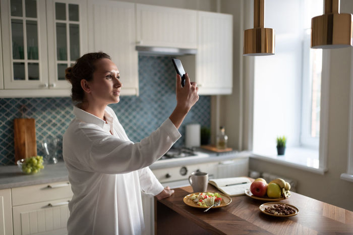 Businesswoman using smartphone for communication in kitchen