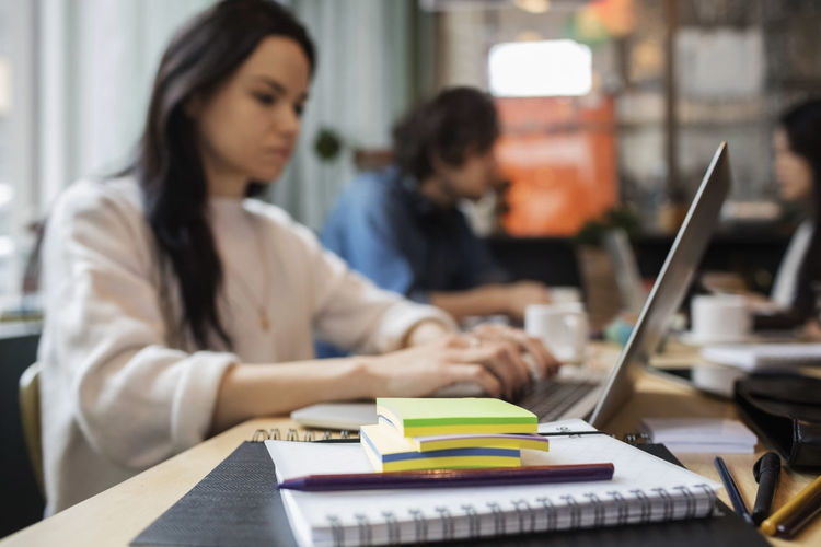 Close-up of office supplies with creative people working at table