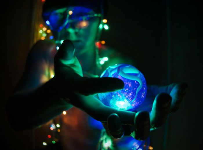 Shirtless man holding illuminated lights