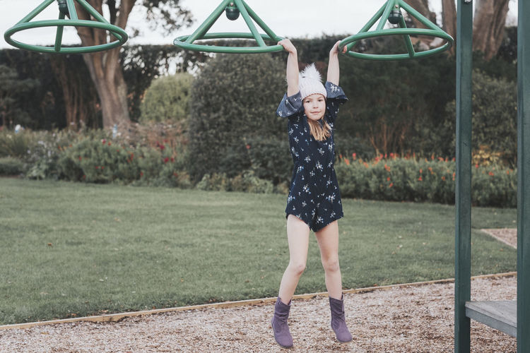 Young girl wearing woolly hat swinging at the playground