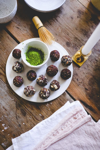 Directly above shot of chocolate pistachio truffles in plate on wooden table